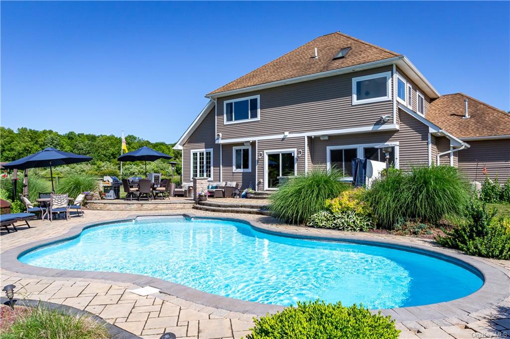 An outdoor oasis with 8 seat hot tub, patio, cooking and lounge areas surrounds the heated inground saltwater pool of this dream