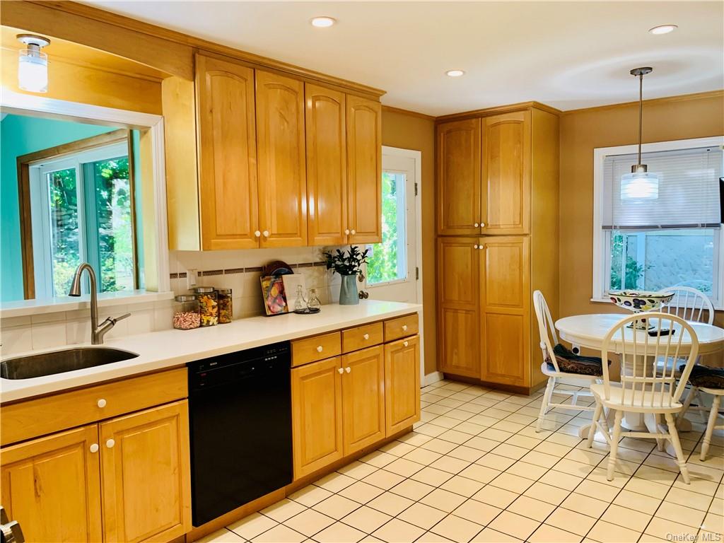 A large dine-in-kitchen with pass-through to the sunroom & leading to a beautiful yard, patio, and outdoor kitchen.